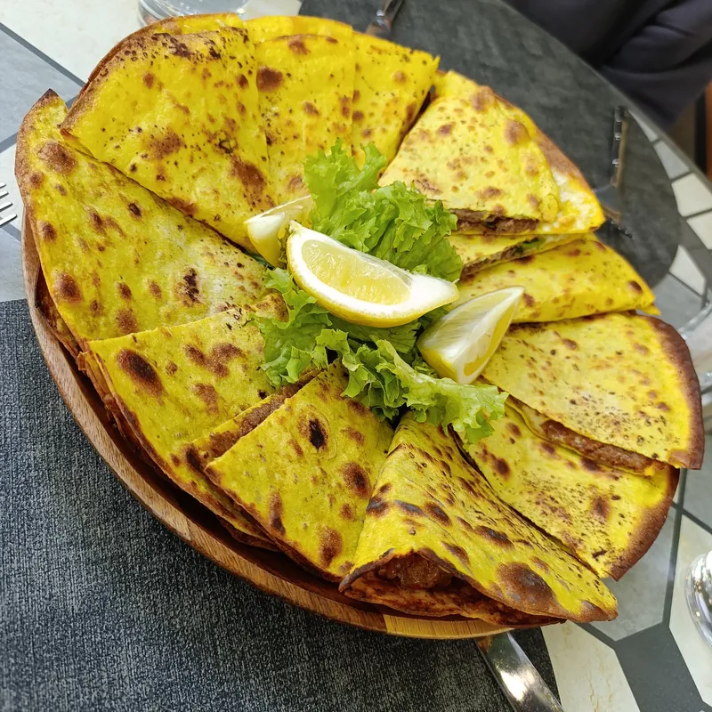 Lahmajo cut in wedges with lemon and greens
