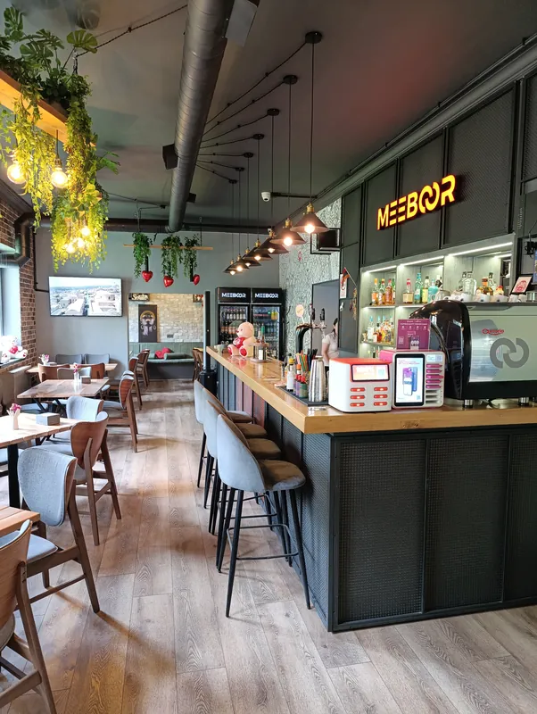 The long bar under the red Meeboor sign, with pendant lamps and greenery