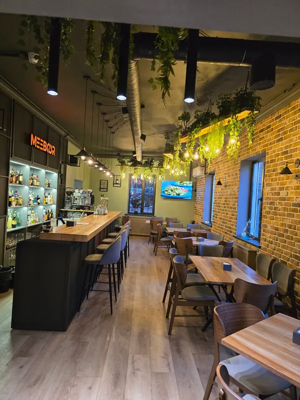 Inside: brick wall, greenery overhead and the long bar